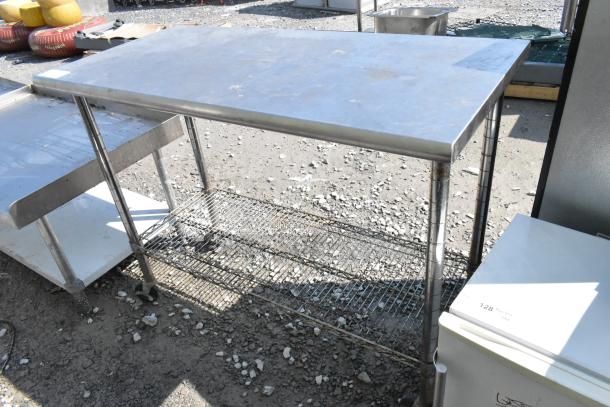 Stainless steel table with wire under shelf on commercial casters, in fair condition, ideal for commercial use.