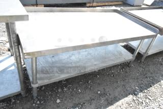 Regency stainless steel equipment stand with metal under shelf, showing wear and outdoor exposure.