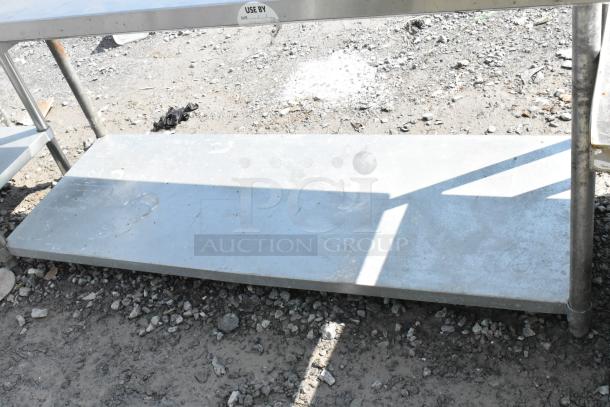 Regency stainless steel table with metal under shelf, used condition, showing surface wear and outdoor placement.