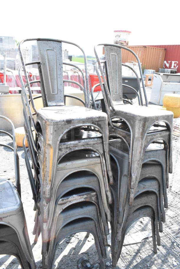 Stack of 19 black/gray metal Tolix style chairs in used condition, outdoor setting. Ideal for industrial decor.