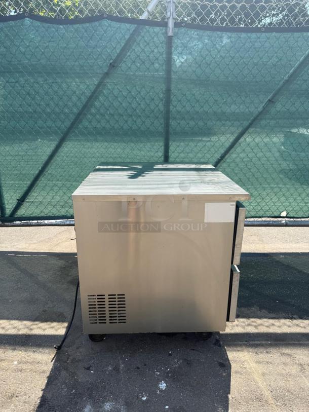 Commercial stainless steel 2-drawer undercounter refrigerator, used condition, front ventilation, metal handles, on casters.