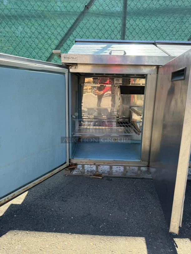 Delfield Model 4472M-30M-A1, 72-inch stainless steel 3-door refrigerated sandwich prep, open door view, outdoor setting.