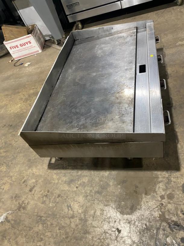 Wolf commercial stainless steel natural gas flat griddle with back and side splash, on legs, used, operational condition shown.