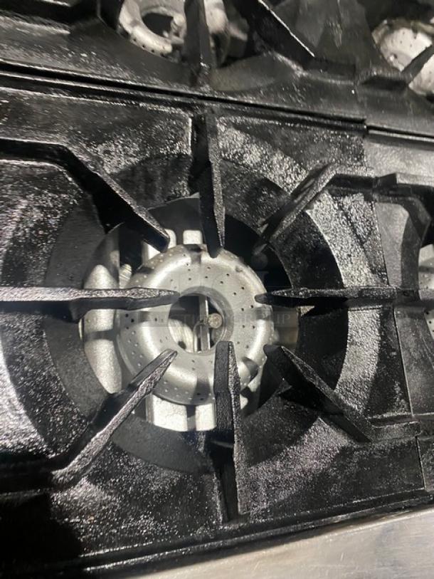 American Range 10-burner gas stove top, black cast iron grates, clean condition, part of a commercial oven combo.