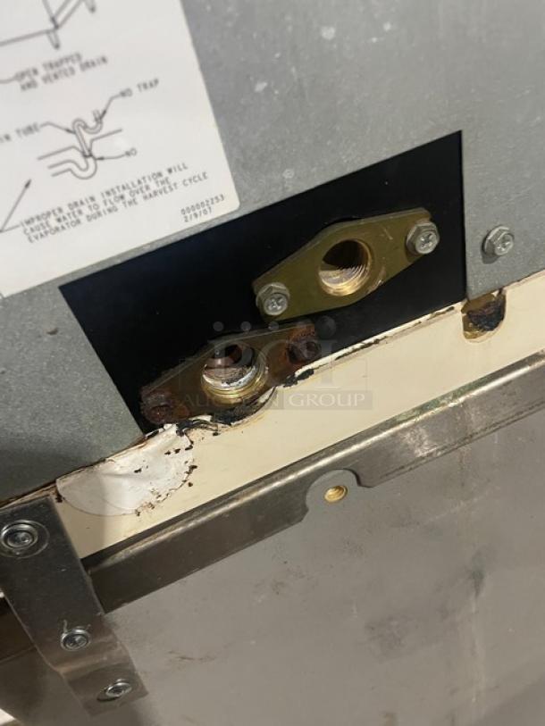 Manitowoc SD0303W ice machine parts with visible wear. Water inlets and mountings shown. Model label partially obscured.