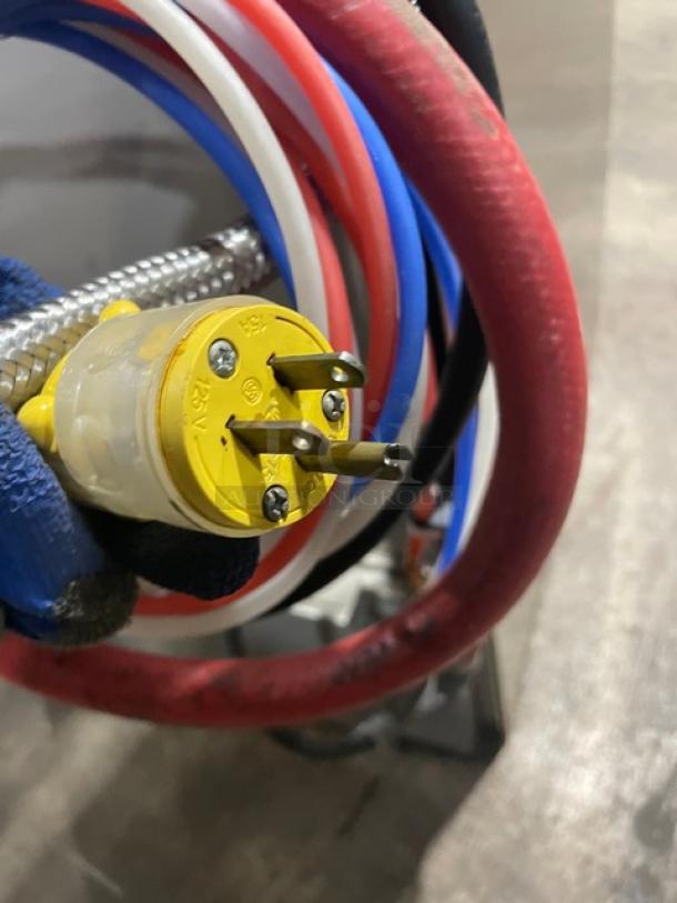Yellow 120V power plug with visible prongs on Hobart LXEC commercial dishwasher. Surrounded by red, blue, and white hoses.