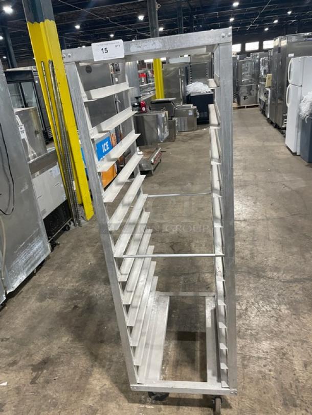 Commercial heavy-duty pan holding/transport rack on casters, aluminum, multiple shelves, auction lot tag visible.