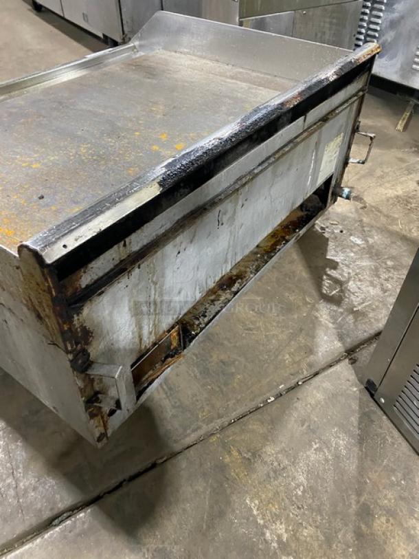 Southbend stainless steel countertop flat griddle with back and side splash, natural gas-powered, on legs. Visible wear and stains.