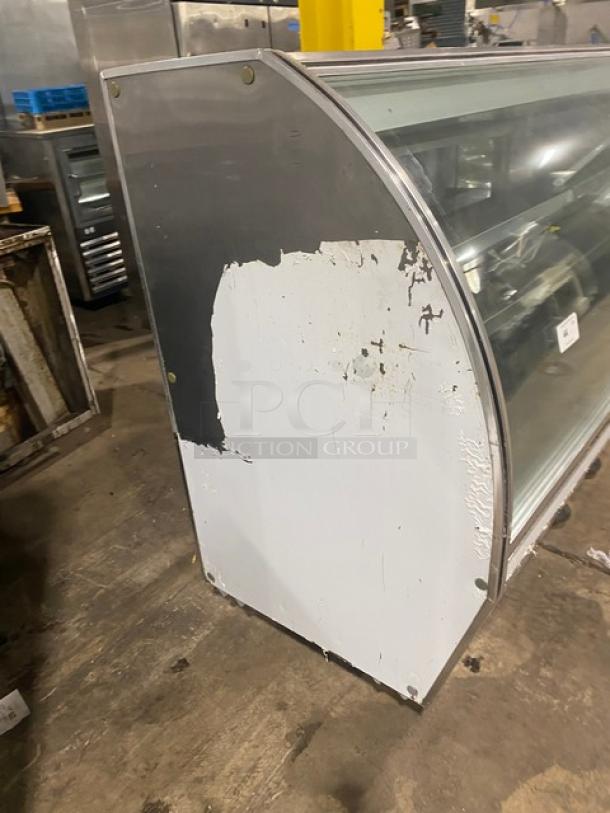 Leader NRHD96R refrigerated deli display case, 96" with curved glass, rear sliding doors, and lower storage. Visible wear.