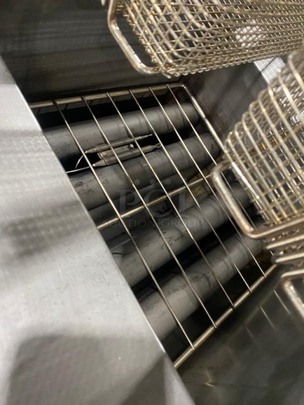 Cookline stainless steel natural gas deep fat fryer with backsplash, basket hanger, and fry baskets on legs.