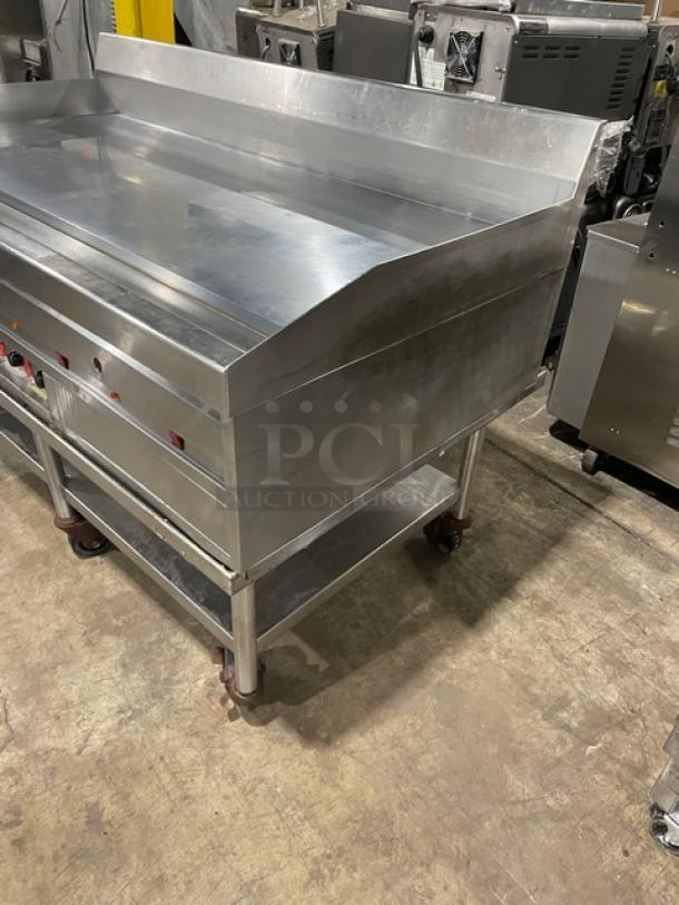 Commercial stainless steel countertop flat griddle with thermostatic controls, back and side splash, undershelf, on casters.
