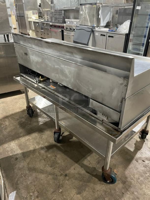 Commercial stainless steel flat griddle with thermostatic controls, back and side splash, undershelf stand, on casters.