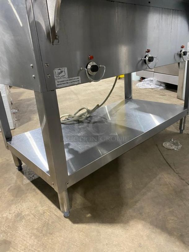 Duke AeroHot Series stainless steel 3-well electric steam table, model E303SWM, with serve-over shelf and undershelf, on legs.