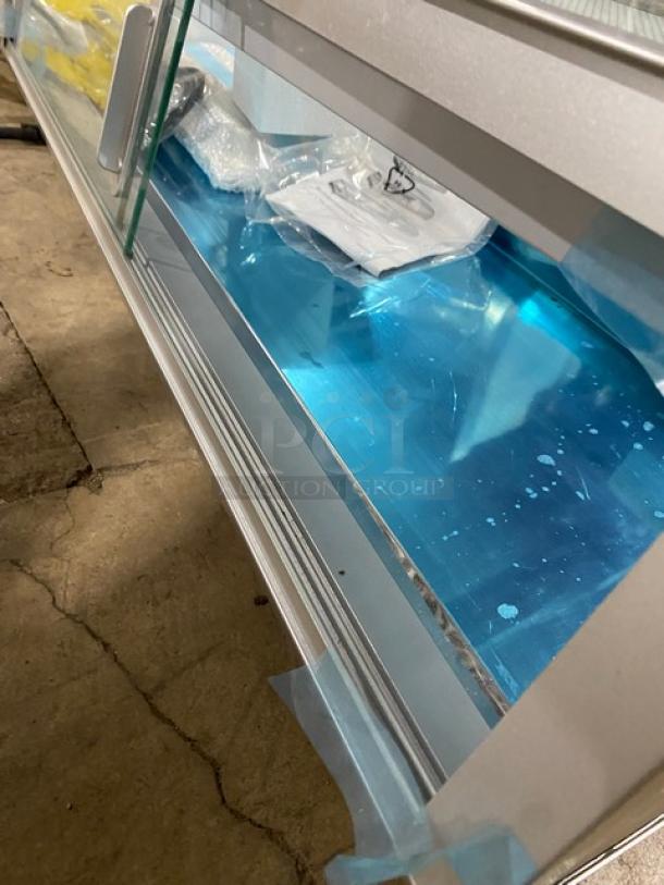 Marchia stainless steel 53" curved glass refrigerated sushi display showcase, Model MSU150S, with LED lights, double glass sliding doors, and new steam table pans. New condition.
