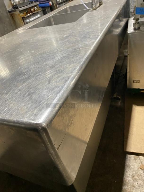 Custom stainless steel double compartment sink workstation with gooseneck swivel faucet and enclosed cabinet base on legs.