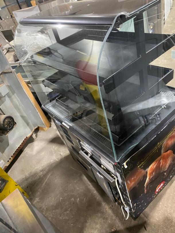 Commercial black curved glass refrigerated display case for bakery items, multi-tier, visible branding, good condition.