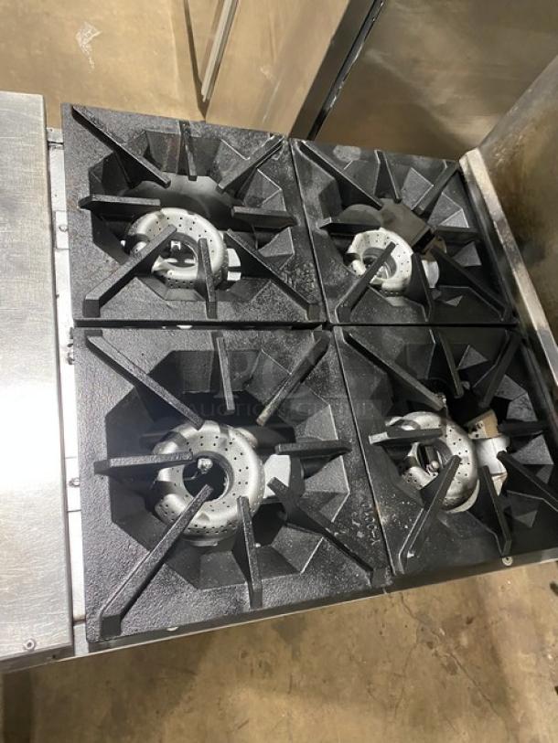 American Range commercial 4-burner stainless steel gas range with overhead salamander shelf, backsplash, and wired oven rack on casters.