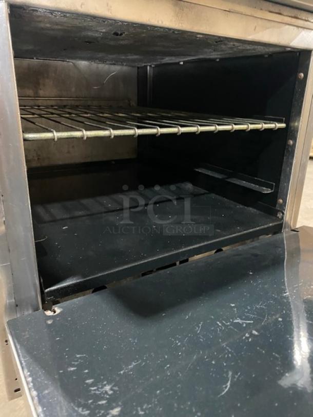 American Range stainless steel 4-burner range/oven combo with wired rack, backsplash, salamander shelf, and casters.