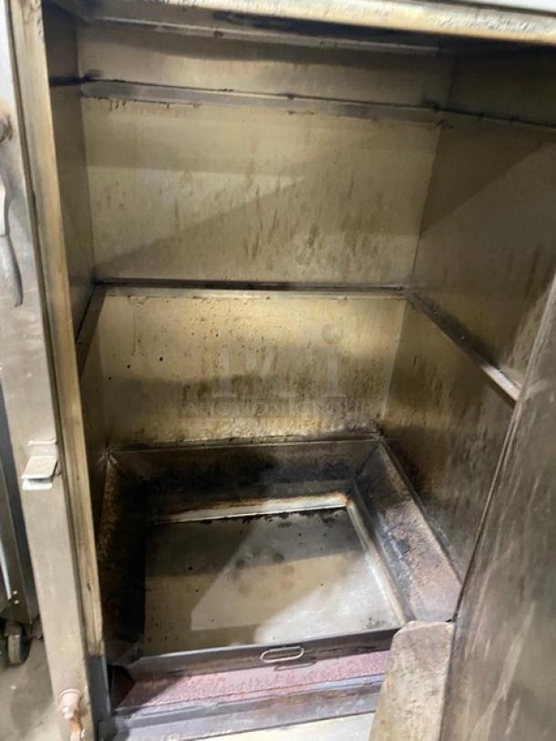 Commercial stainless steel natural gas smoker oven with right-side hinged door and legs, showing interior condition.