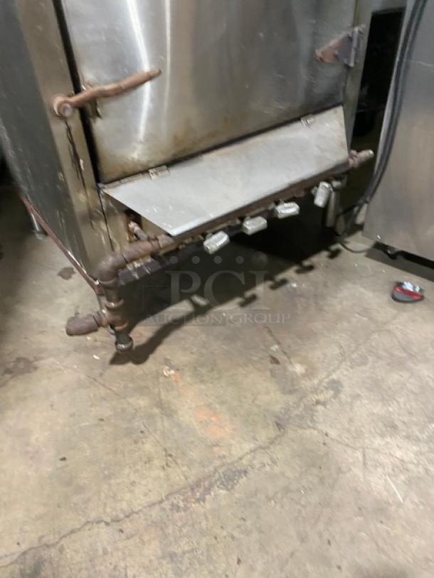 Commercial stainless steel smokehouse with right-side hinged door, natural gas powered, on legs, used condition.