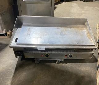 Commercial stainless steel countertop flat griddle with thermostatic controls, back and side splash, natural gas powered.