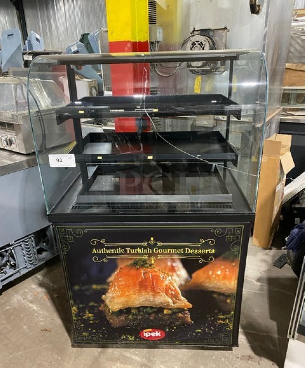 Commercial black curved glass refrigerated display case with multi-tier shelving for gourmet desserts, branded with "Authentic Turkish Gourmet Desserts" by Ipek.