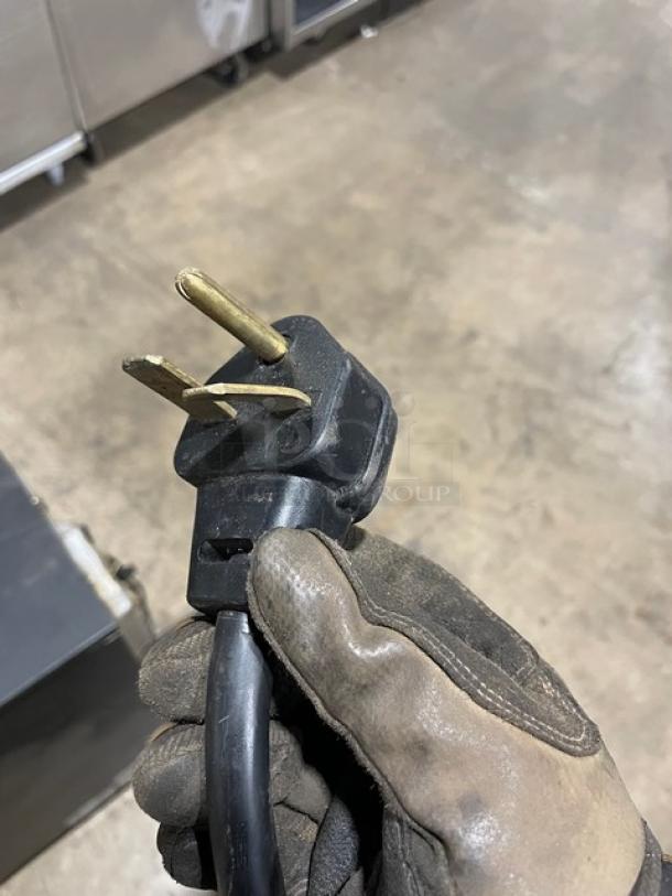 Alt text: Black power plug from MerryChef Eikon E2S rapid cook oven, 208/240V 1 phase, shown in gloved hand.