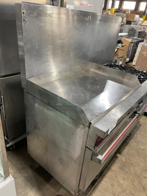 Vulcan commercial stainless steel flat griddle with split top, 4-burner range, double oven combo, backsplash, and wired oven racks.