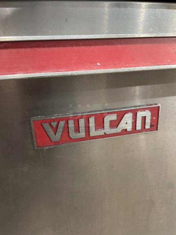Vulcan stainless steel gas flat griddle, split top with 4-burner range, double oven, backsplash, wired racks, on legs.