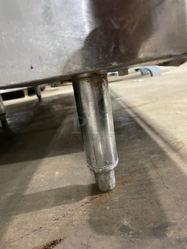 Vulcan commercial flat griddle range leg detail, stainless steel, natural gas, with slight rusting, on concrete floor.