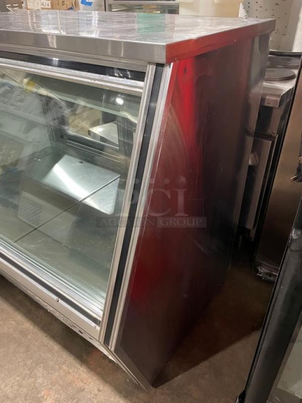 Leader stainless steel slanted glass refrigerated deli merchandiser with rear sliding doors and lower storage. Excellent condition.