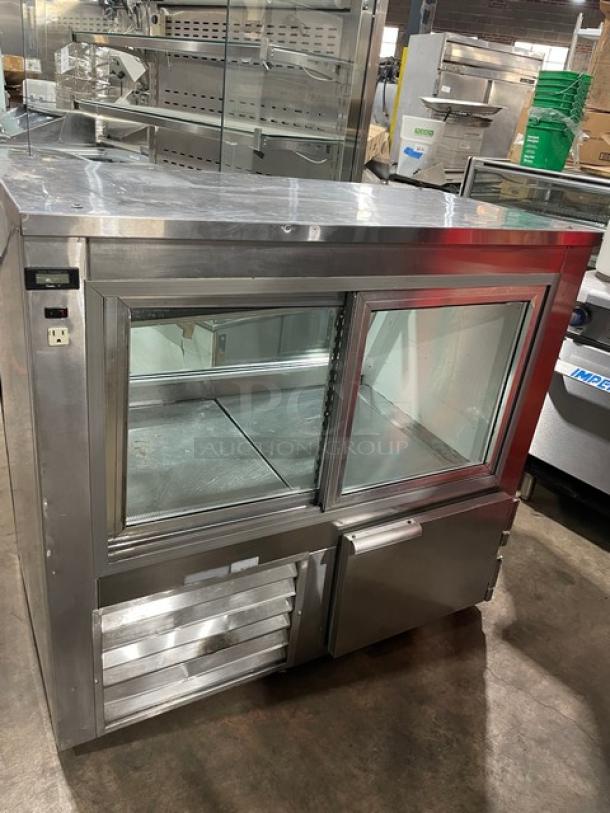 Leader Commercial Stainless Steel Slanted Glass Refrigerated Display Showcase with rear sliding doors and lower storage.