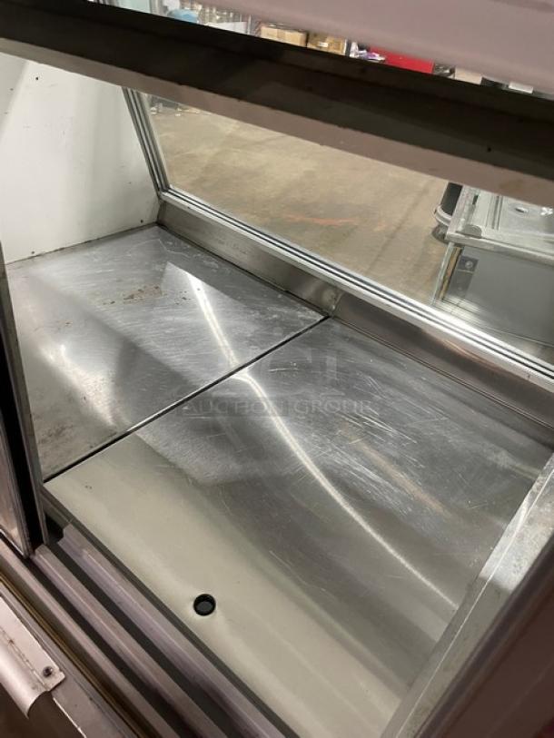 Leader stainless steel slanted glass refrigerated display case, rear access sliding doors, overstock storage, good condition.