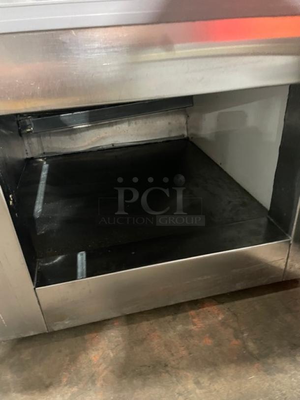 Leader stainless steel refrigerated display case with slanted glass, rear access sliding doors, and lower storage compartment.