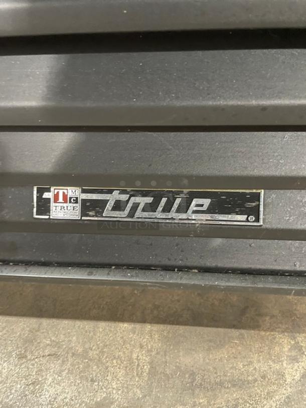 True GDM-72 commercial refrigerator logo on appliance. Black triple glass swing door, poly coated wire racks, 115V.