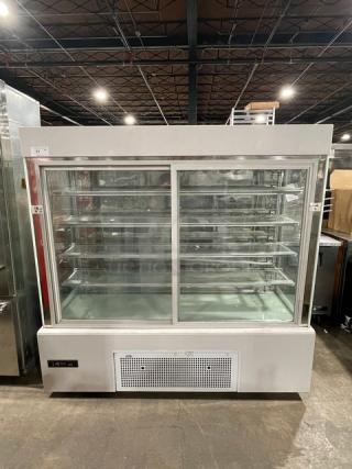 Commercial white refrigerated bakery display with multi-tier glass shelves, double sliding doors, on casters, excellent condition.