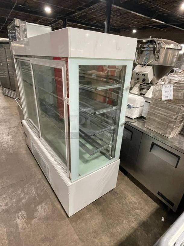 Commercial white glass bakery display case with sliding doors, multiple tiers, on casters. Used condition, ideal for showcasing.