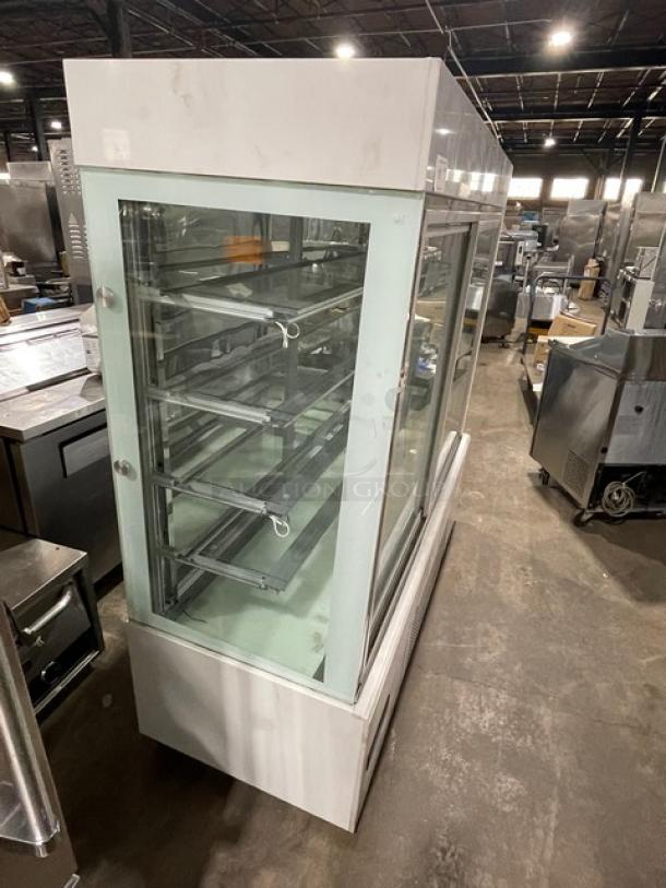 Commercial white glass refrigerated bakery display with multiple tiers, double sliding doors, on casters. Used condition.