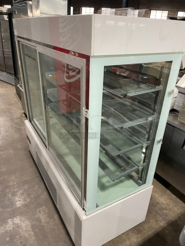 Commercial white glass refrigerated bakery display showcase with multi-tier shelves, double sliding doors, and casters.