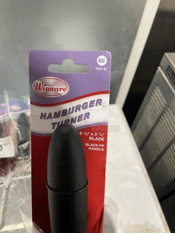 Winco TKP-61 stainless steel hamburger turner with black grip handle, new in packaging. Blade size: 5 1/8" x 2 7/8".