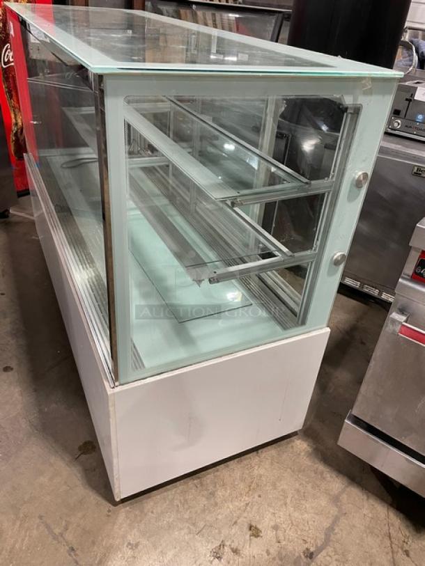 Commercial white glass refrigerated bakery display with multi-tier shelves and rear double glass sliding doors.