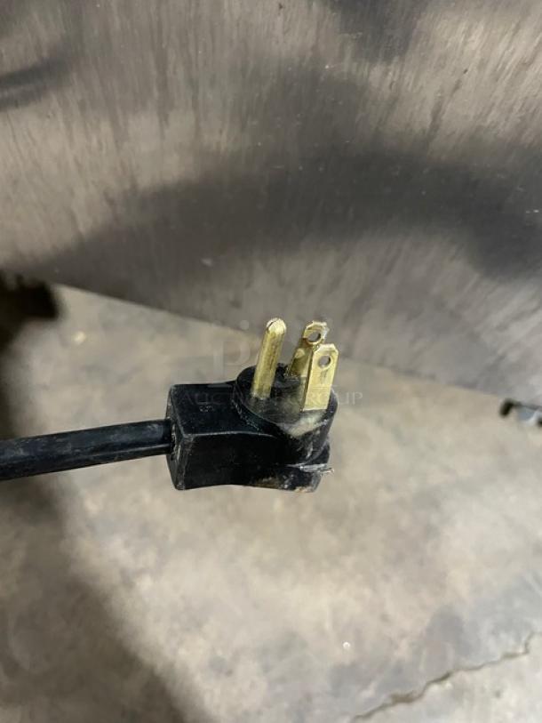 Close-up of a 115V plug for a Beverage-Air UCR27 stainless steel undercounter refrigerator, showing a solid three-prong connector.