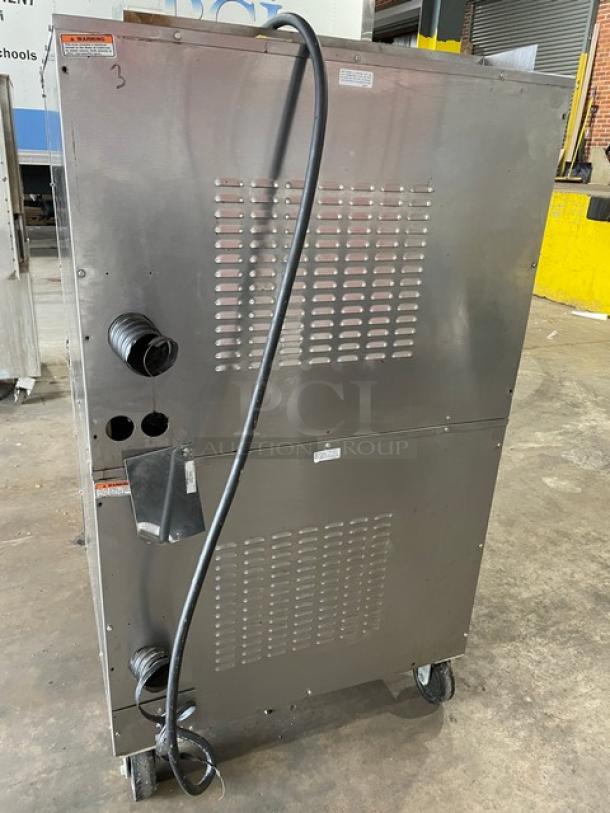 Vulcan commercial stainless steel electric double-stacked convection oven, wired racks, on casters, rear view.