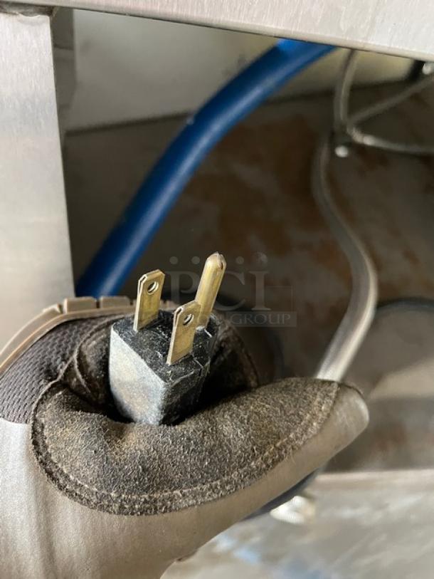 Alt text: Blue gas connector hose on Rational SCC62G combi oven, held with a gloved hand.