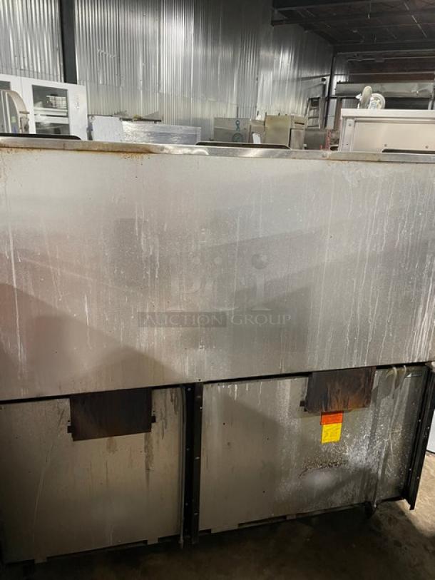 Vulcan commercial stainless steel range with 10 burners, double oven, overhead salamander shelf, and wired racks. Natural gas-powered. Rust markings visible.