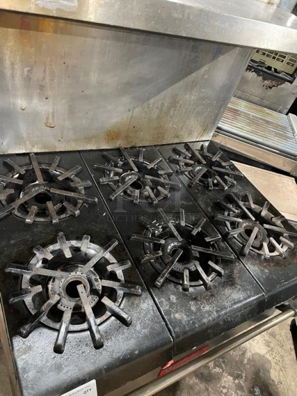 Vulcan commercial stainless steel 6-burner range with oven combo. Features backsplash, overhead salamander shelf, and wired oven rack.