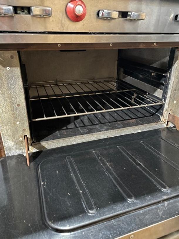 Vulcan commercial stainless steel gas range/oven combo with 6 burners, backsplash, overhead salamander shelf, and wired oven rack.