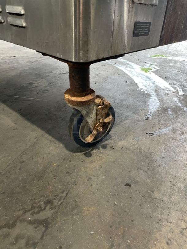Blodgett stainless steel convection oven on rusted caster. Part of a double-stacked natural gas unit, includes wired racks.