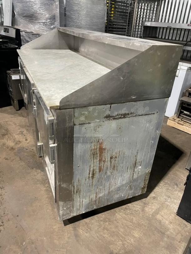 Bari commercial stainless steel 3-door refrigerated pizza prep table with marble-style worktop, on casters, shows wear.