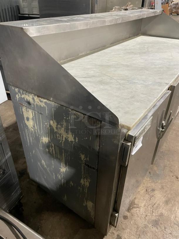 Bari commercial 3-door refrigerated prep table with marble style worktop. Stainless steel, worn surface, on casters.